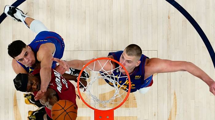 Miami Heat forward Jimmy Butler (22) shoots the ball against Denver Nuggets forward Michael Porter Jr. (top) and center Nikola Jokic (right) during the second half in game one of the 2023 NBA Finals.